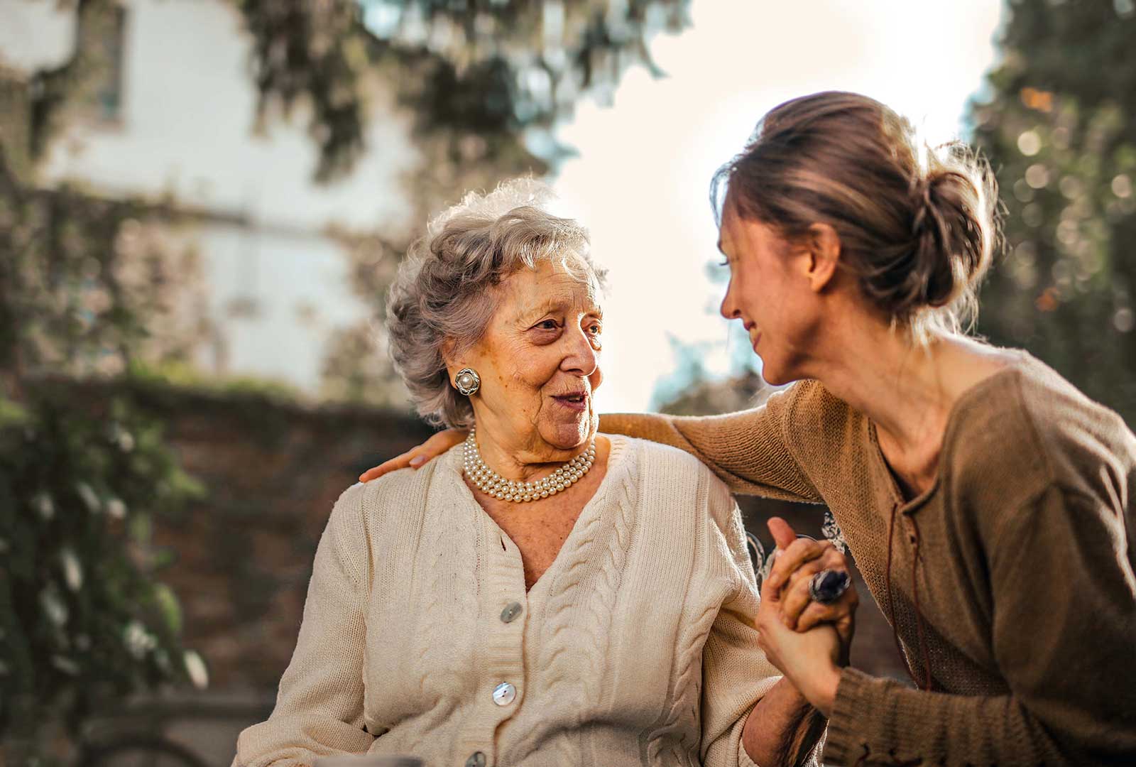 woman with arm around seated senior woman